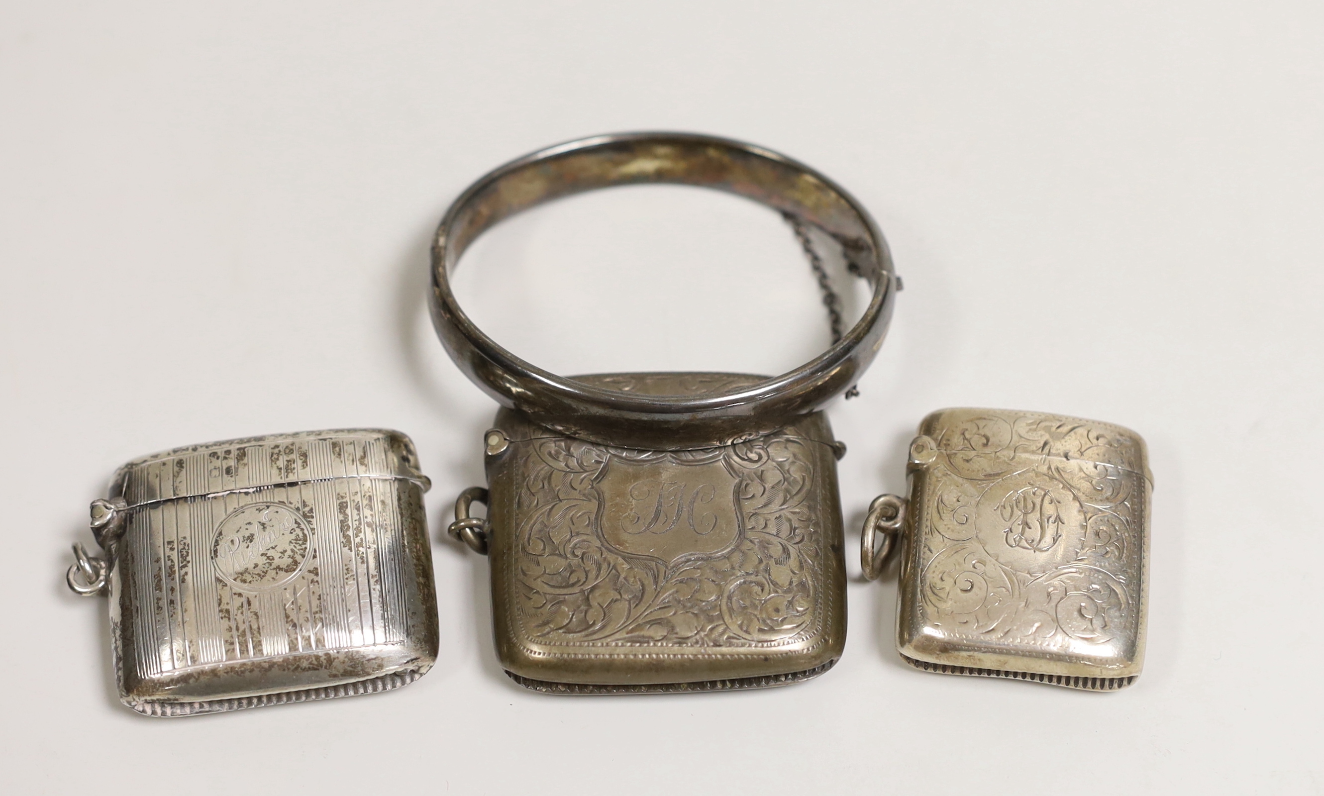 Three assorted late 19th/early 20th century chased silver vesta cases and a chased silver hinged bangle.